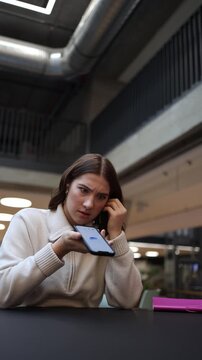 Vertical screen young woman questions ChatGPT about a work problem holding her phone with a doubtful expression as the ai reply seems incorrect creating a relatable moment of confusion and hesitation