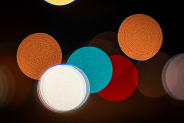 Colourful and bright glowing overlapping circles with black background, the effect of blurry bokeh moving city traffic at night.