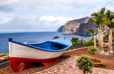 Traditional Painted Fishing Boat, Tenerife. A colourful painted fishing boat on display near the ocean in Los Gigantes, Tenerife, Canary Islands, a picture postcard scenic view of the island.