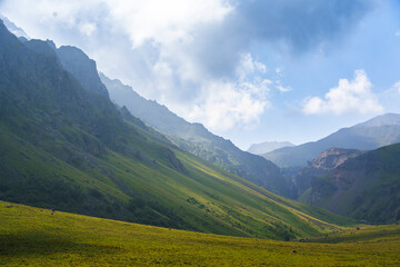 Wide mountain valley with steep green slopes under blue sky