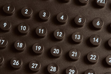 Close up of calendar day numbers. Black calendar with round numbers. Toned.