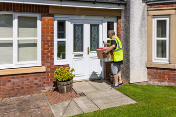 Online shopping courier ringing doorbell while holding parcel