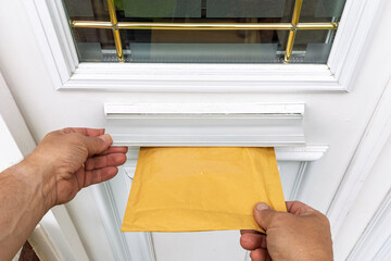 Point of View of Courier's Hand Pushing Padded Mailer Into Door Letterbox