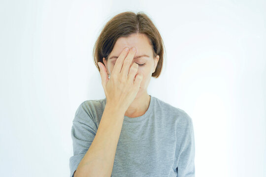 Woman massaging the third eye acupressure point GV 24.5 between eyebrows for migraine relief. Symbolizes energy meridian therapy, traditional Chinese medicine technique, and ancient headache remedy.