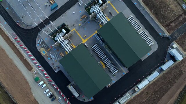 Drone footage capturing vast electrical infrastructure including National Grid transformers, synchronous condenser units, solar panels and overhead power lines in Wisbech UK