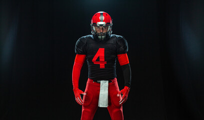 American football player wearing full gear on a black background sports portrait with dramatic lighting ideal for posters and advertising