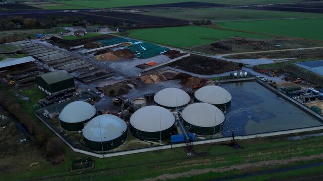 Aerial drone view of rural biogas energy plant, power station using renewable agricultural waste in countryside, domes and electricity generation near Wisbech, UK