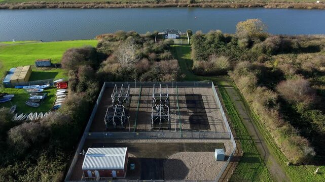Aerial drone perspective of a small electrical sub station with transformers for grid power and energy relay near the River Nene, Kings Lynn, UK