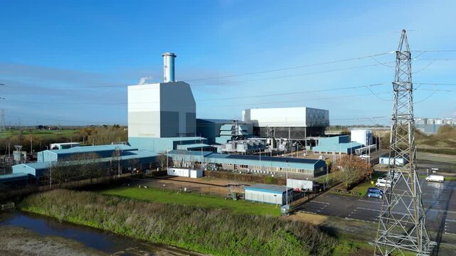 Wide drone view of Kings Lynn industrial power plant and transmission substation with smoke emissions on a clear day