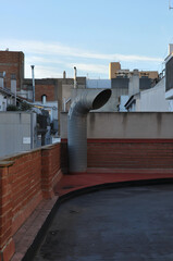 Ventilation pipe on urban rooftop at sunset