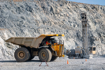 Open pit mine gold ore industry. Massive Mining Dump Truck and Drilling Equipment at Quarry Site © Parilov