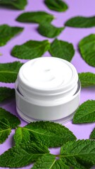 White jar of cream surrounded by fresh, green mint leaves