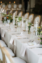 Elegant wedding reception table setting with candles, crystal glassware, and fresh floral arrangements, creating a luxurious and romantic atmosphere for a sophisticated celebration.