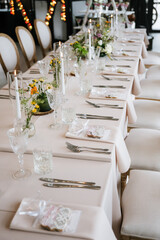 Elegant wedding reception table setting with candles, crystal glassware, floral centerpieces, and neatly arranged cutlery—luxurious celebration décor in soft, romantic tones.