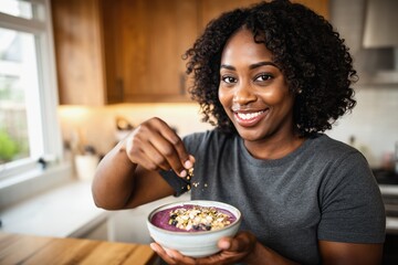 Radiant woman with natural curly hair smiling warmly while seasoning a smoothie bowl