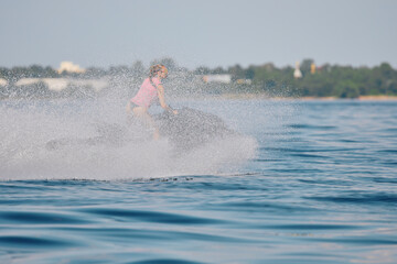 athletic girl rides a jet ski with splashes, she is having fun on a jet ski with splashes in the waters of the Gulf of Finland, Russia, St.Petersburg
