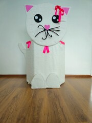 Beckoning cat. A closeup shot of a hanging white cat  with a red ribbon against a white background. cat made of cardboard. 