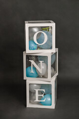 vertical photo decor for the celebration of the first birthday. Transparent cubes labeled ONE, which contain colorful balloons. background for the first birthday.