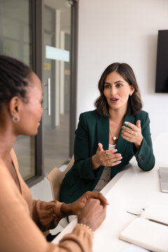 Fototapeta Positive young Latin businesswoman talking to partner at workplace, meeting with consultant for advice, expertise, speaking to colleague, discussing cooperation on project. Vertical shot