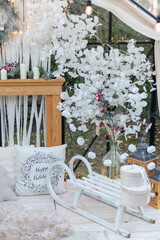 Cozy white Christmas winter decorations with wooden sleigh and pillow