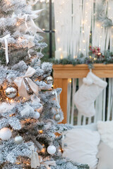 Close-up of white flocked Christmas tree decorated with silver ornaments and bows