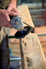 Worker Sanding Wooden Beam with Power Tool