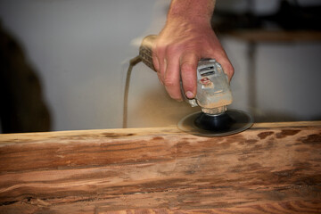Worker Sanding Wooden Beam with Power Tool