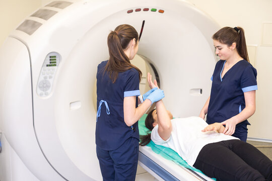 CT scan technologist overlooking patient in Computed Tomography scanner during preparation for procedure. Woman patient going into CT scanner.