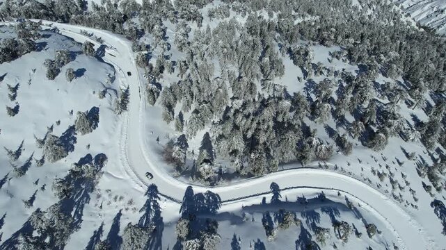 Drone aerial  4k resolution footage view of winter snowy road passing through mountain forest  . Winter landscape Troodos Cyprus
