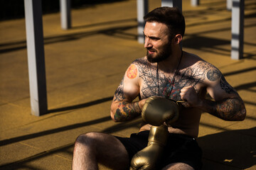 Muscular bodybuilder handsome man with naked torso trains triceps in a crossover cable exercise...