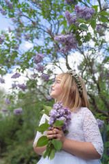 Fototapeta premium Smiling Girl in First Communion Dress with Lilac Blossoms