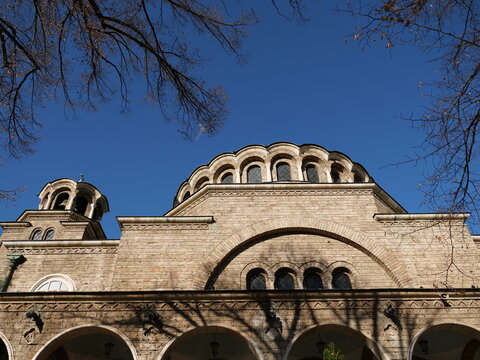 Low angle architectural shot of the stone facade, domes, and bell tower of the historic
neo-Byzantine style St. Nedelya Church in Sofia, Bulgaria, under a clear blue sky.