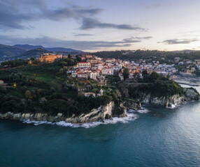 Aerial view of the medieval castle perched atop a cliff, ancient buildings cascading towards the sea, where the azure waters meet the rugged coastline, Agropoli, Campania, Italy.