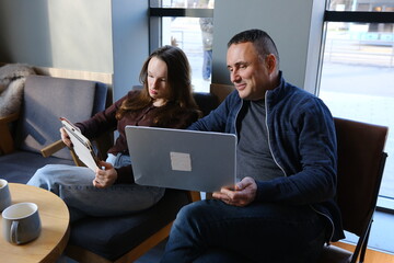 Smiling team professional employees working together on computer discussing online technology data solutions at work. Two young busy diverse coworkers business people using laptop at office .