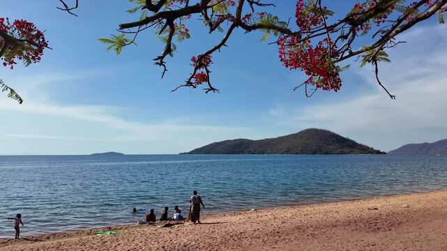 Cape Maclear  Lake Malawi Africa. 01, 12.2025. Video.  Holidaymakers on the sandy beach at Cape Maclear within the Malawi National Park ssouthern Malawi Africa.