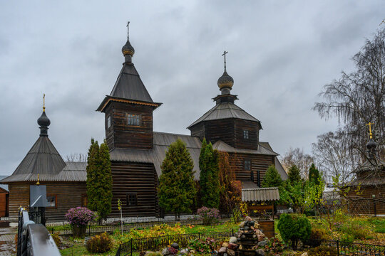 Beautiful wooden church in Murom surrounded by lush greenery and cloudy skies