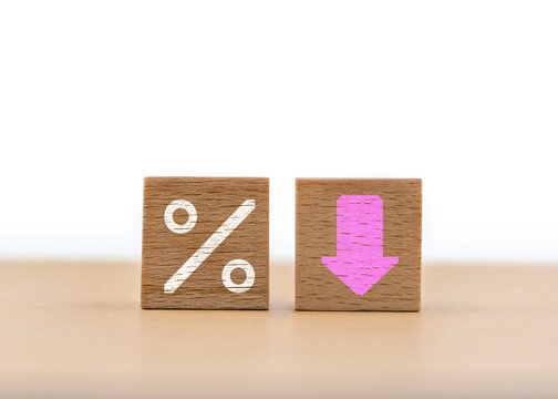 Wooden blocks showing percentage symbol and downward arrow representing financial decrease or discount trend