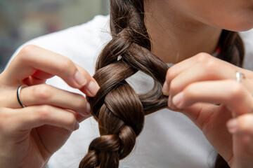 Obraz premium młoda dziewczyna czesze włosy i plecie warkocze