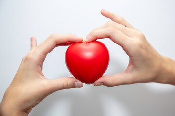 Czerwone serduszko trzymane w dłoniach dziewczyny na białym tle © hunter76