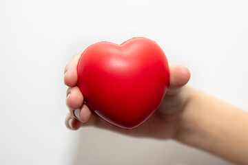 Czerwone serduszko trzymane w dłoniach dziewczyny na białym tle © hunter76