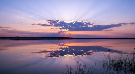 A beautiful sunset over a calm lake, with the clouds and sky reflected in the water. The sun's rays burst through the clouds, creating a dramatic and peaceful s
