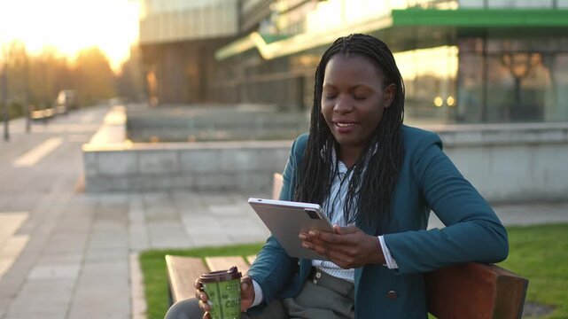 Successful african american businesswoman using tablet computer on a bench