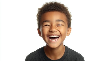 A young boy shows a wide smile with his teeth showing capturing a moment of happiness. His curly hair frames his face in a bright environment highlighting his cheerful expression.