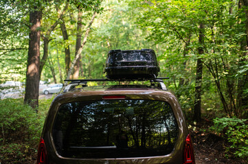 Man Attaching or Opening a Black Roof Box on a Car in the Forest