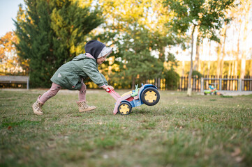 Toddler Girl Pushing a Toy Tractor Walker in the Backyard