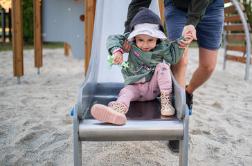 Adult Helping a Toddler Girl Slide Down the Slide at a Playground