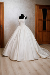 Elegant bridal gown displayed in a cozy room with wooden accents and soft lighting