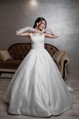 Fototapeta premium Elegant bride in a stunning white ball gown poses gracefully in a stylish indoor setting