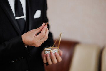 Groom holds wedding ring in elegant box while preparing for ceremony at formal venue