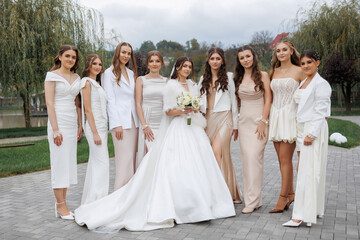 Bridal party poses in elegant outfits by a serene outdoor setting during a wedding celebration